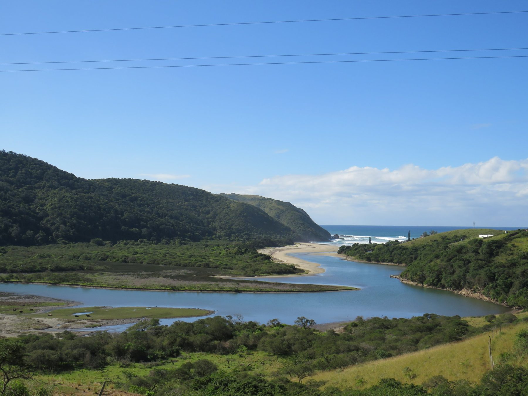 A river meeting the sea below green hills
